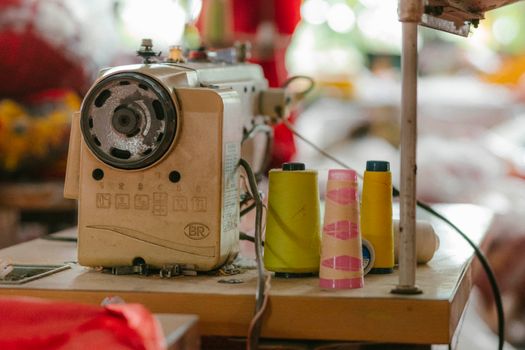 Machine à coudre vintage avec bobines de fil colorées sur une table de travail dans un atelier de couture.