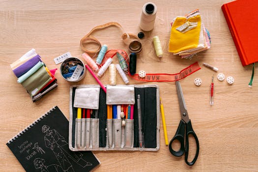 Trousse d'écolier avec crayons, ciseaux et fournitures de couture sur une table en bois.